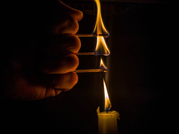 istock Matches burning to light a candle on black background 1266625728