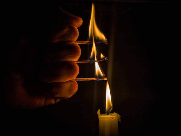 istock Matches burning to light a candle on black background 1266626291