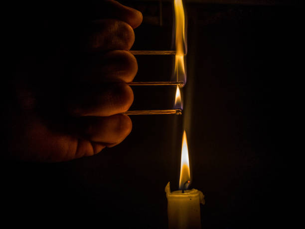 istock Matches burning to light a candle on black background 1266626344