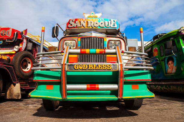 Manila, Philippines - November 6, 2024: A jeepney drives through a bustling Manila street filled with various vehicles on a clear sunny day.