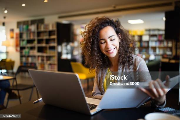 Young Afro American Woman Sitting At Table With Books And Laptop For Finding Information Stock Photo - Download Image Now
