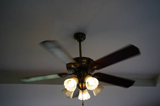 Ceiling fan and light overhead with big leaf blades in a room