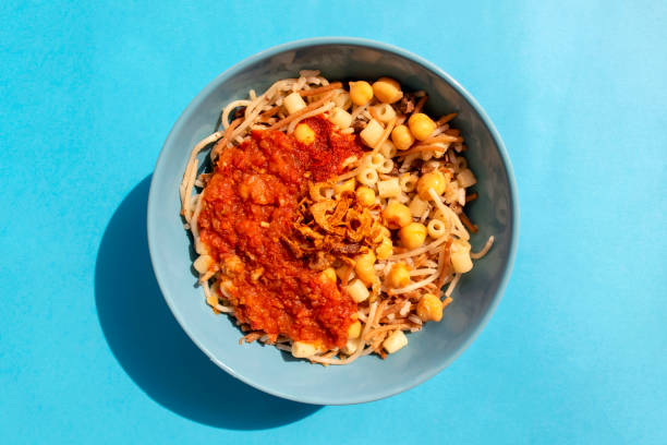 Egyptian national Koshari food in a turquoise plate on blue background Famous traditional Arabic, Egyptian dish - Koshari. National Kushari in a turquoise plate on blue background. Top view. koshary stock pictures, royalty-free photos & images
