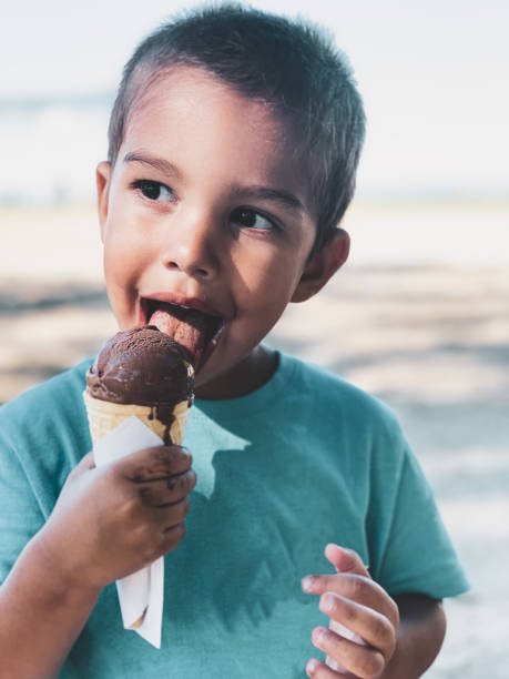 istock Toddler boy eating a chocolate ice cream wafer cone on a beach 1266633052