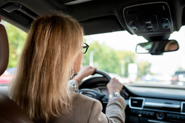 istock Woman with blond hair looking through front window while driving for meeting 1266635481