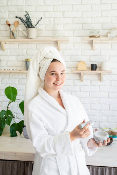 istock Happy young woman applying face scrub on her face in her home kitchen 1266636374