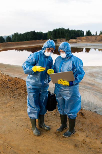 istock Young female ecologists in protective workwear standing on polluted soil or clay 1266639462