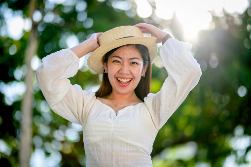 Image portrait of a young and beautiful woman in hat at public park with back lighting.