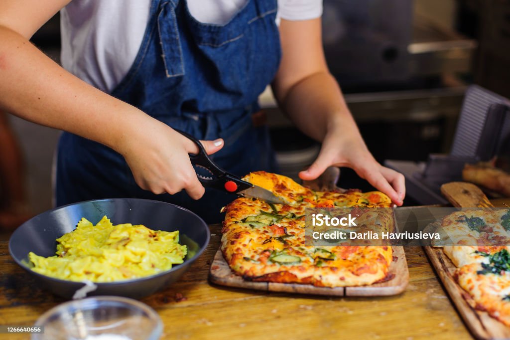 Chef hands cuts pizza with kitchen scissors Scissors Stock Photo