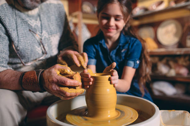 istock Pottery workshop. Grandpa teaches granddaughter pottery. Clay modeling 1266641128