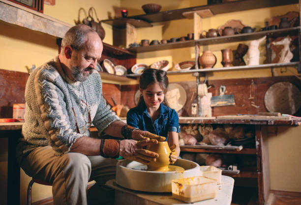 istock Pottery workshop. Grandpa teaches granddaughter pottery. Clay modeling 1266641488