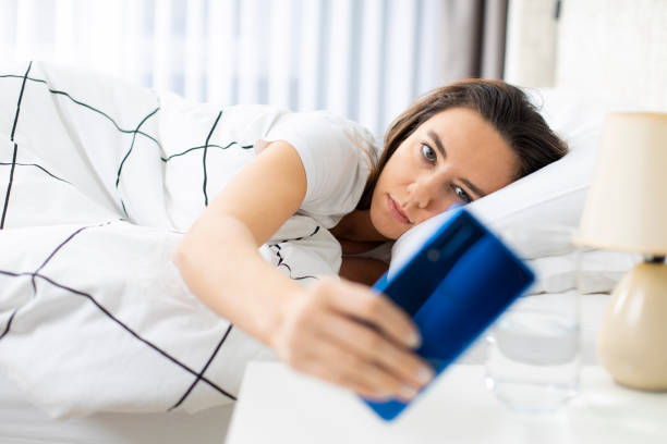 istock Young woman using mobile phone on bed 1266641719