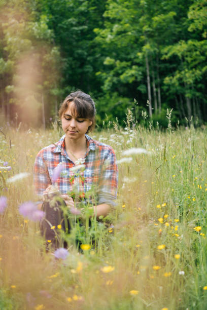 istock Young woman sits in mountain meadow holding note book and pencil 1266642020