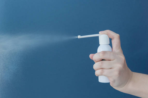 istock hand holds white bottle with spraying medicine on blue background. 1266643217