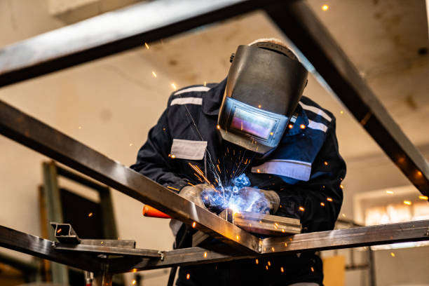 Senior worker working with welding tool Senior man welding at his work place.  He is dressed in work suit. welding torch stock pictures, royalty-free photos & images