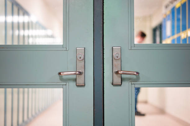 Student returning to school. School reopening by following social distancing rule after covid-19 pandemic lockdown. Locked door and handle see through blurred student lockers and student standing at background in high school or college. Students return to school and are in class full-time learning and education concept. doorknob stock pictures, royalty-free photos & images