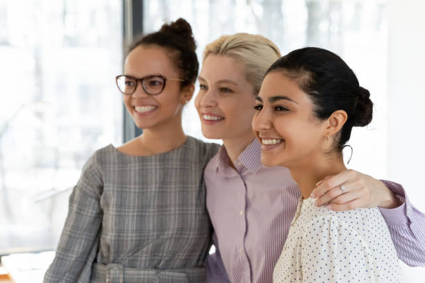 istock Smiling multiethnic female colleagues hug show unity at work 1266648580