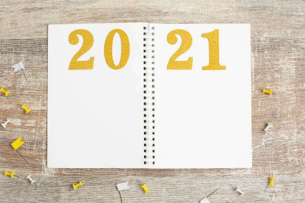 istock Gold number 2021 on open notebook on wooden background, 1266648671