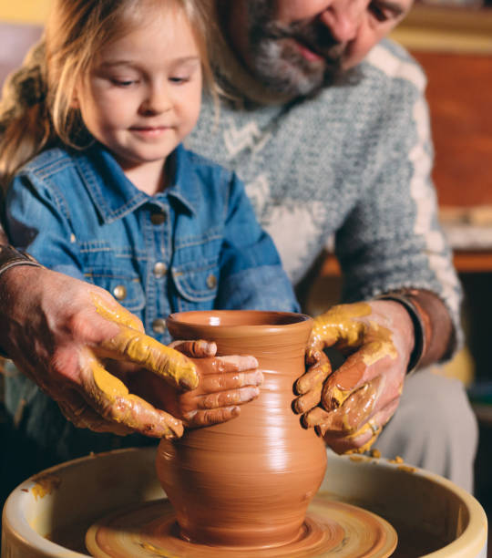 istock Pottery workshop. Grandpa teaches granddaughter pottery. Clay modeling 1266650923