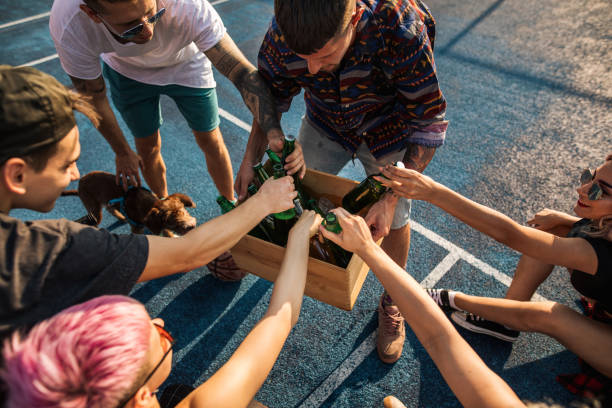 Carefree friends taking beer out of a wooden crate on an outdoor party Alternative young group of modern people enjoying time together outdoors on a sports terrain. beer crate stock pictures, royalty-free photos & images