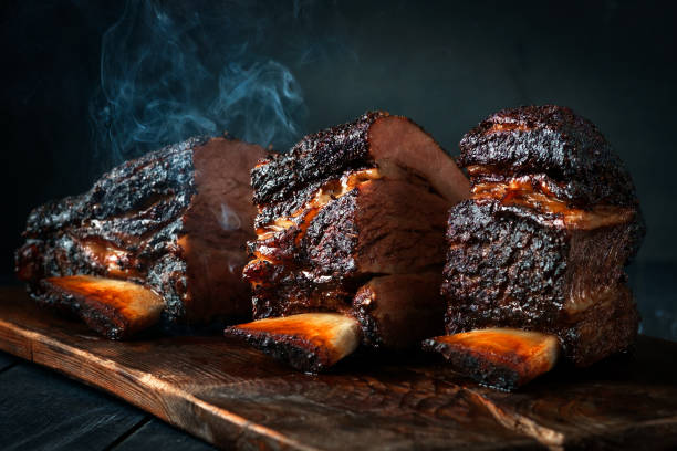 taglia un grande pezzo di petto di manzo affumicato alle costole con una crosta scura. barbecue classico del texas - affumicato foto e immagini stock