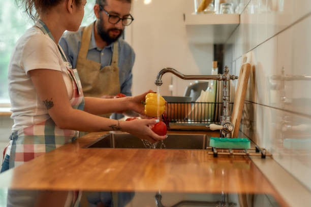 istock Young couple washing vegetables in the kitchen while preparing ingredients for dinner. Cooking at home concept 1266657850