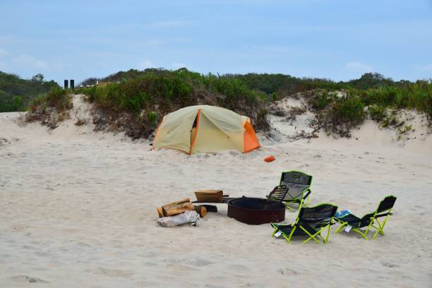 Fire Pit and Camping Tent Campsite A dome tent in the background, and yes they are still asleep, with a fire pit and folding chairs for their night time gathering eastern shore sand sand dune beach stock pictures, royalty-free photos & images