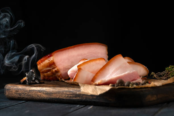 vientre de cerdo ahumado con un trozo entero de humo y cortado en rodajas en una tabla de madera - smoked bacon fotografías e imágenes de stock