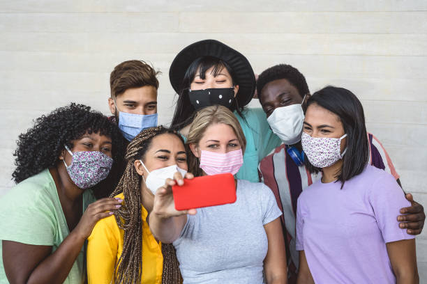 grupo de jovens usando máscara facial tirando selfie com smartphone móvel ao ar livre - amigos millennials com diferentes raça e cultura retrato - conceito multirracial e tecnológico - mobile phone group of people human face latin american and hispanic ethnicity - fotografias e filmes do acervo