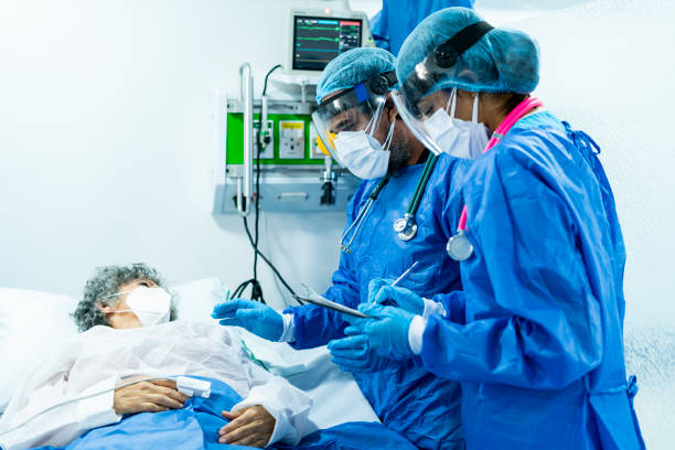 Pair of doctors checking an inpatient in intensive care while wearing their biosecurity suits Pair of Latino doctors between 30 and 49 years old, check on a patient hospitalized in intensive care while wearing their biosecurity suits during the COVID 19 pandemic inpatient stock pictures, royalty-free photos & images