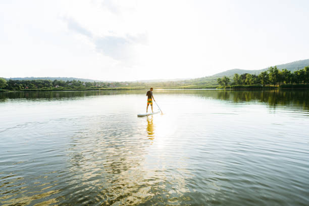 istock Young man stand-up paddleboarding on the lake 1266668435