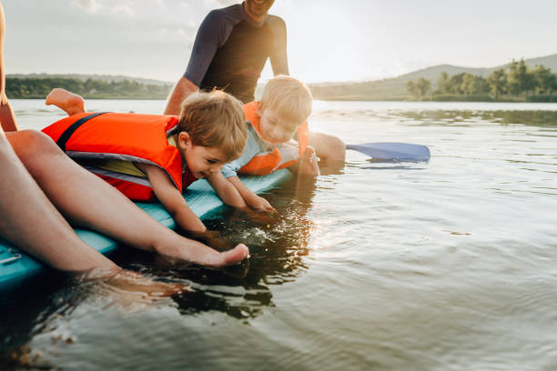 Little paddlers Photo of two cute brothers and their parents paddling on the lake,  and enjoying summer days far from the hustle of the city. water activities stock pictures, royalty-free photos & images