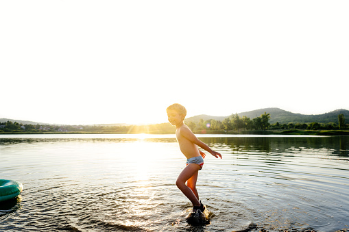 Photo of a cute little boy, splashing feet, and playing in the lake.