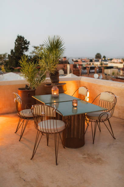 Table for romantic dinner on rooftop terrace in evening. Moroccan style, vintage lamps, candles, cactus flower, twilight.