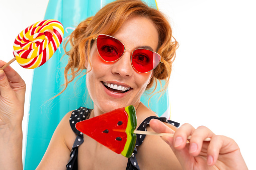 portrait of a sunny retro girl with lollipops on the background of a surfboard.