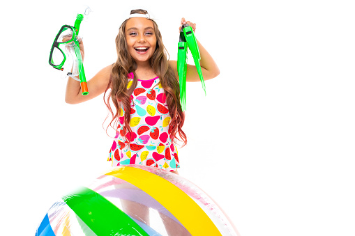girl holds glasses and scuba diving flippers near an inflatable ball on a white background.