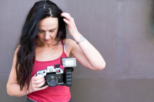 Interested young woman checking an analog photography camera.
