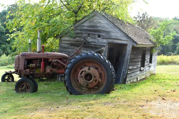 A very old tractor in front of an equally old farm building.