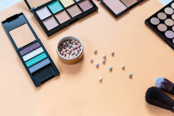 istock Makeup background. Eye shadow palette, powder, brushes, lipstick on yellow background. Flat lay, top view with copy space. Fashion, beauty, makeup, cosmetics. 1266691829