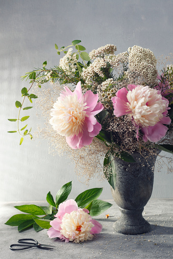 Floral bouquet arrangement, mixed pastel flowers and greenery in a rustic stone vase. Vintage style.