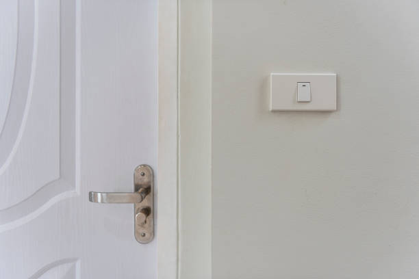 istock White lighting switches on wall and door handle on wall 1266694182