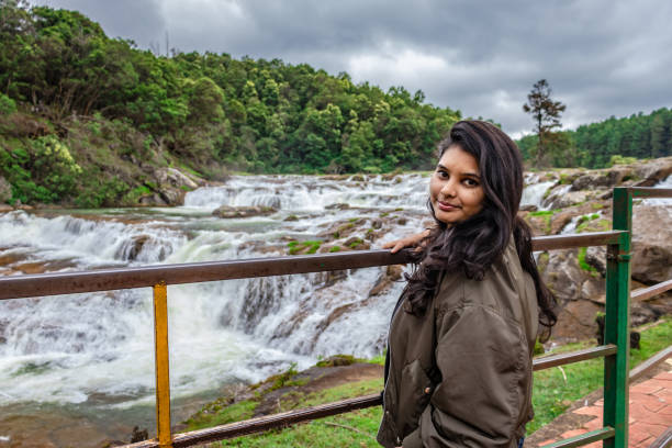 istock girl isolated standing at serene waterfall with lush green forest 1266700799