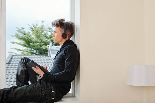 istock Pensive teenager on window sill 1266704168