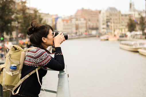 asian young woman taking picture of canal in Amsterdam