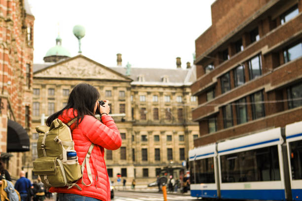 viaggiatore asiatico scattare foto con palazzo reale amsterdam sullo sfondo - dam foto e immagini stock