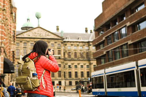 asian traveler taking picture with  royal palace Amsterdam in background