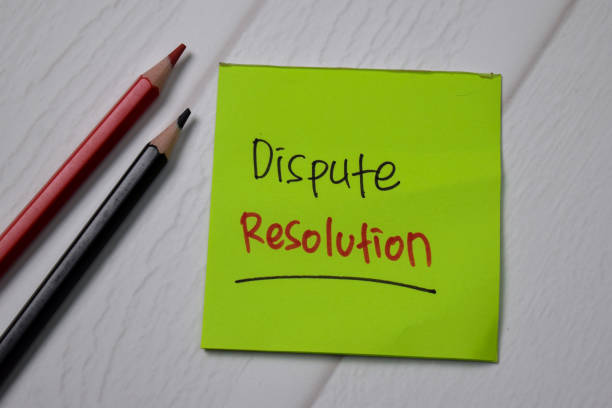 istock Dispute Resolution write on sticky note with magnifying glass isolated on wooden table. 1266708913