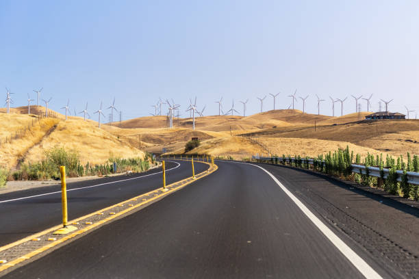 istock Freeway crossing through golden hills covered in wind turbines 1266713809