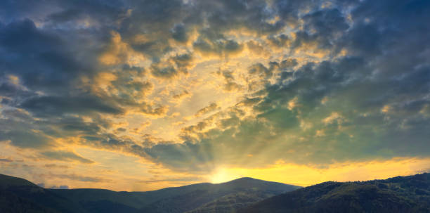 istock Mountains with beautiful sunset with bright setting sun breaking through the clouds 1266716485