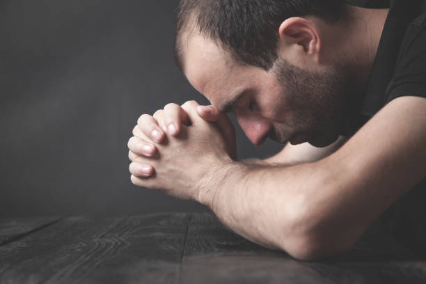istock Caucasian man praying in the dark room. 1266717239